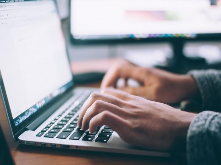 Hands typing on a laptop