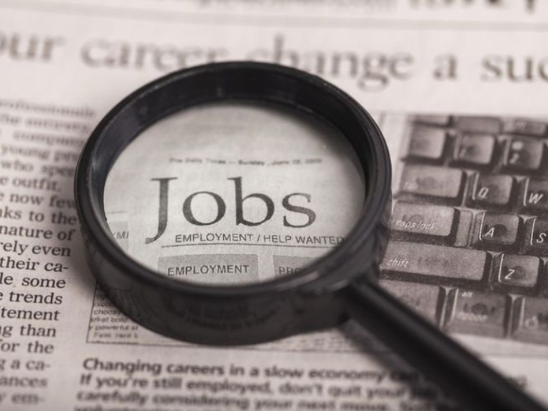 Magnifying glass over the jobs section of a newspaper
