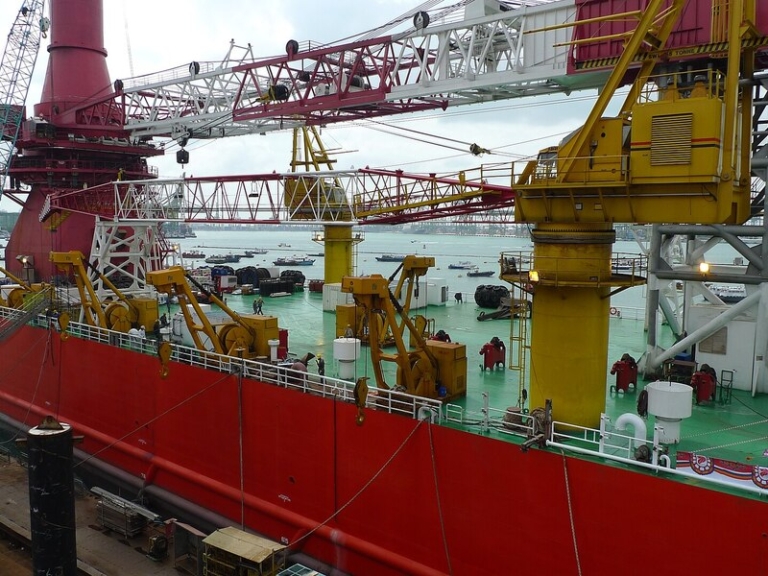 Foreign marine engineer in Singapore reviewing ship engineering drawings at a shipyard
