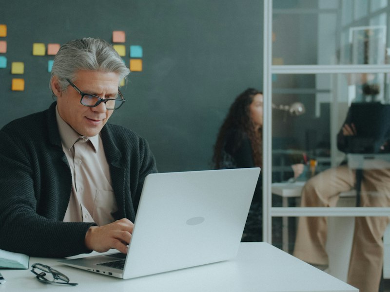 Older employee with grey hair working on a laptop, illustrating senior worker CPF contribution rates in 2027