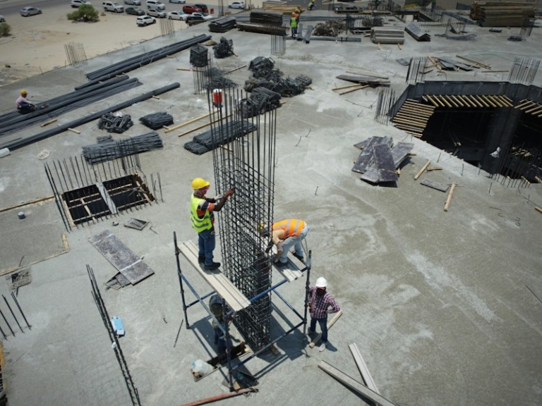 Construction workers standing on a building site, illustrating the MOM levy waiver for Work Permit holders