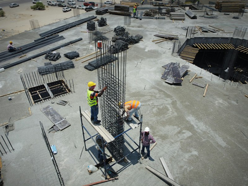 Construction workers standing on a building site, illustrating the MOM levy waiver for Work Permit holders