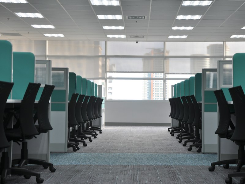 Rows of empty black office chairs at grey cubicles in an unoccupied office