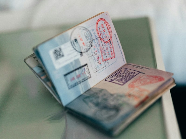 An open passport with multiple colourful ink stamps on the pages
