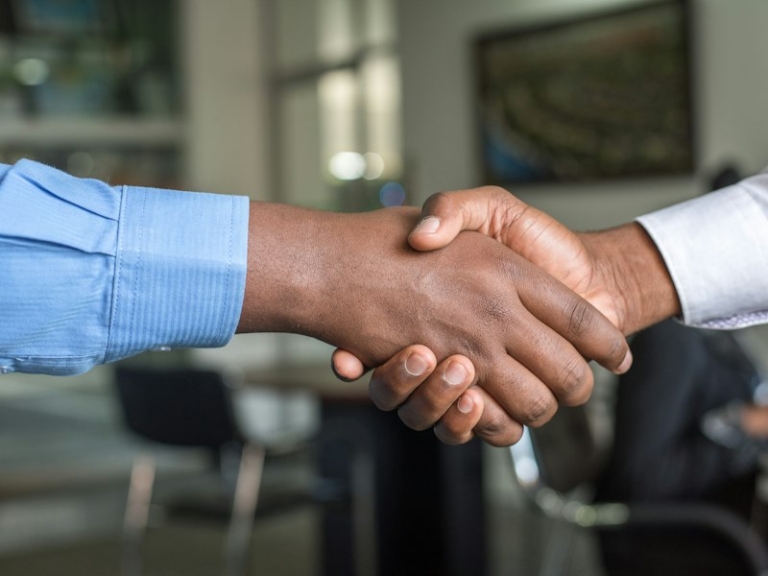 Two professionals shaking hands, illustrating an S Pass change of employer in Singapore