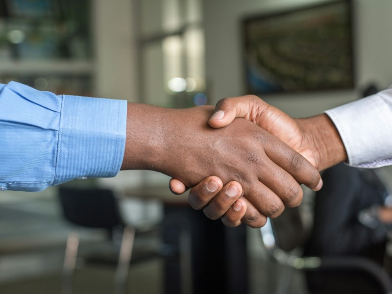 Two professionals shaking hands, illustrating an S Pass change of employer in Singapore